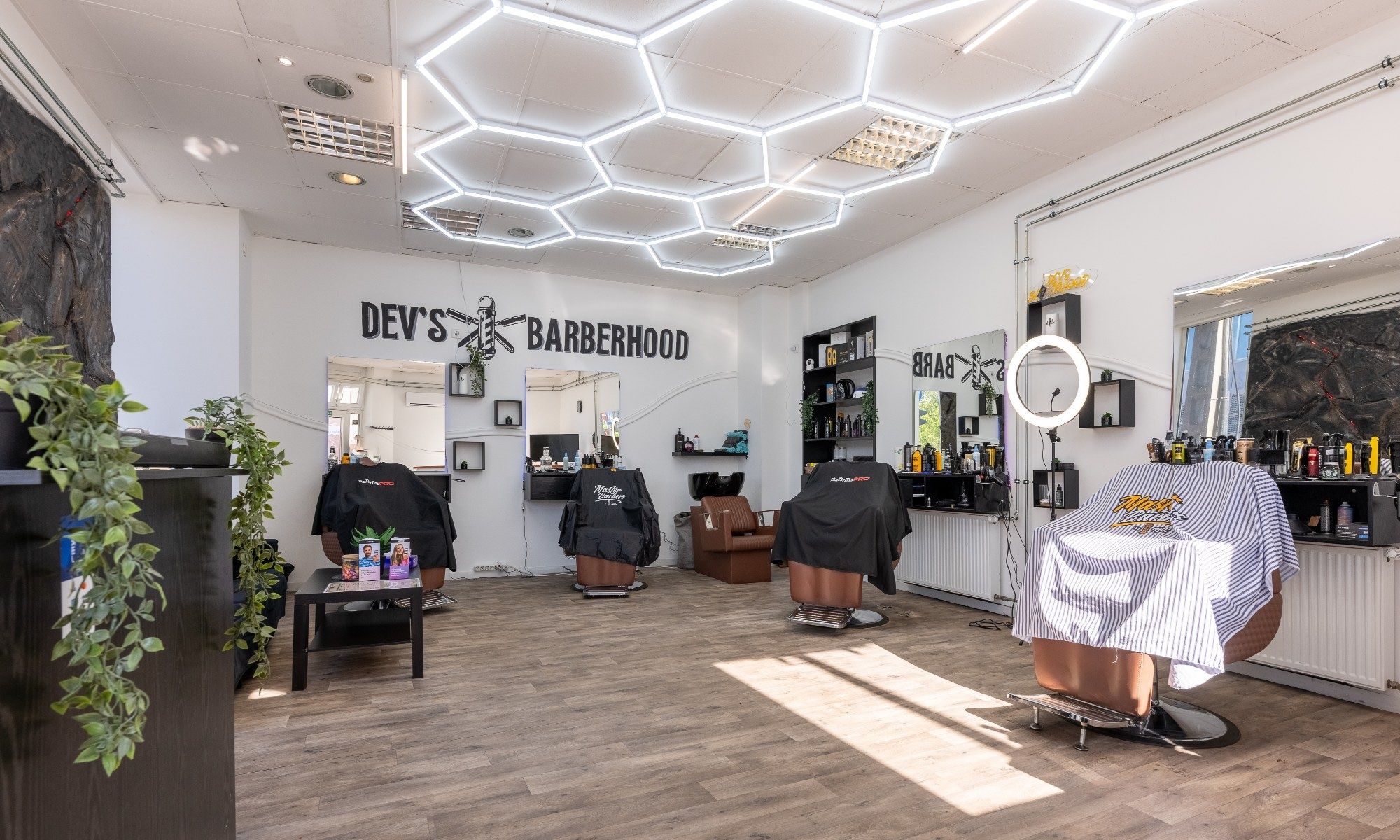 A szalon teljes belső tere: négy barberszék, tükrök, a falon Dev's Barberhood felirat.