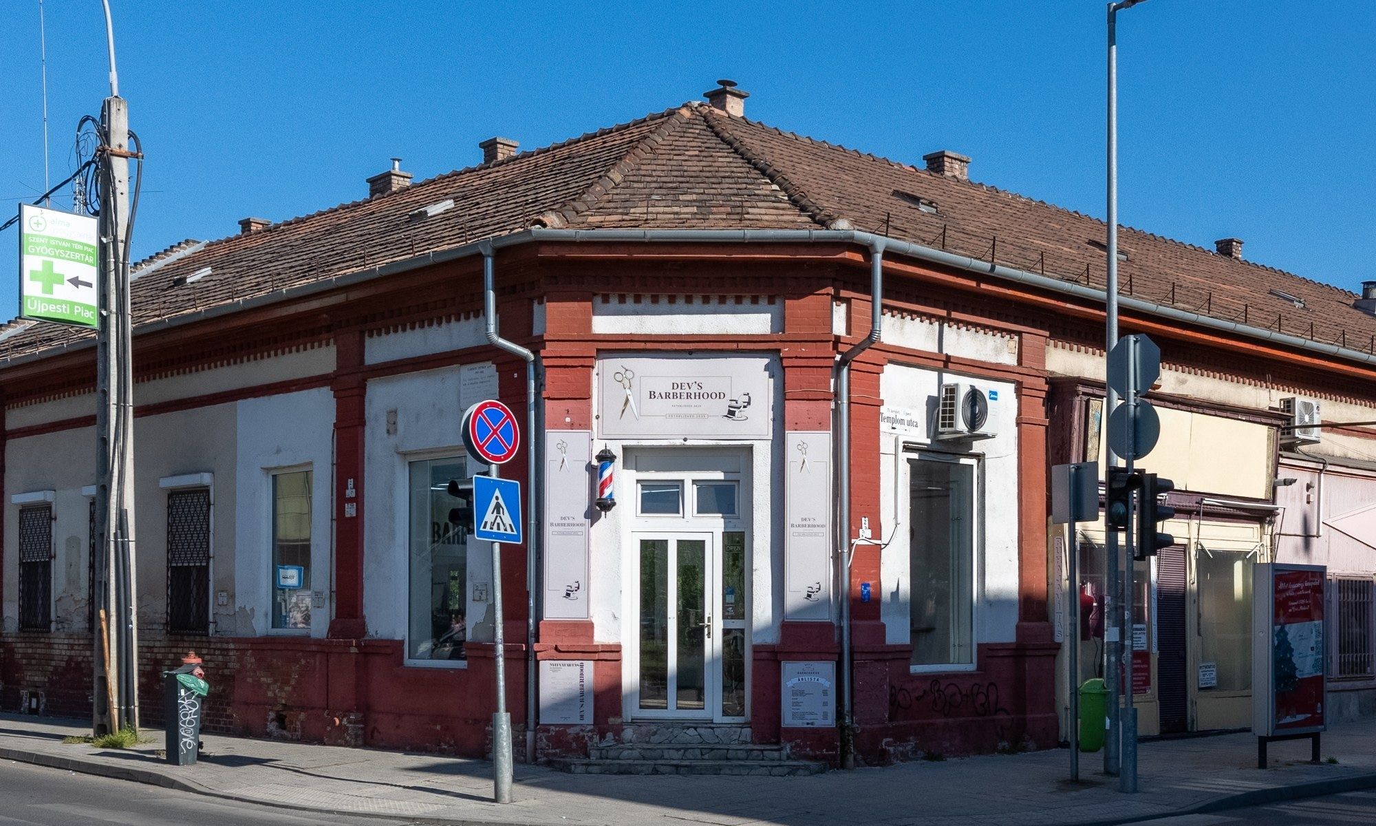 A szalon kívülről: piros-fehér, földszintes sarokház, a sarki bejárat mellett borbélyoszlop.